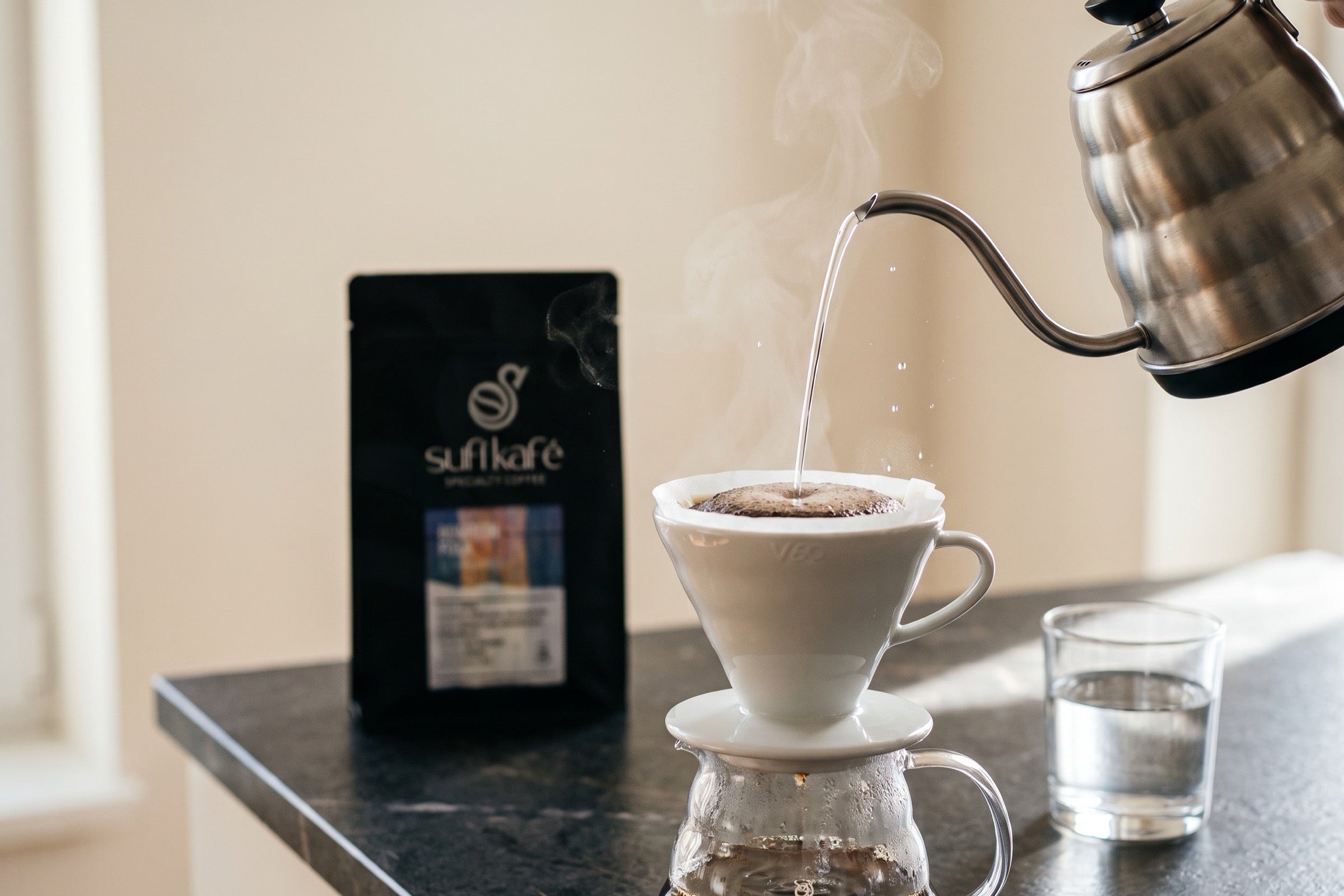 Agua vertida sobre un V60 junto a una bolsa de café de Sufí Kafé