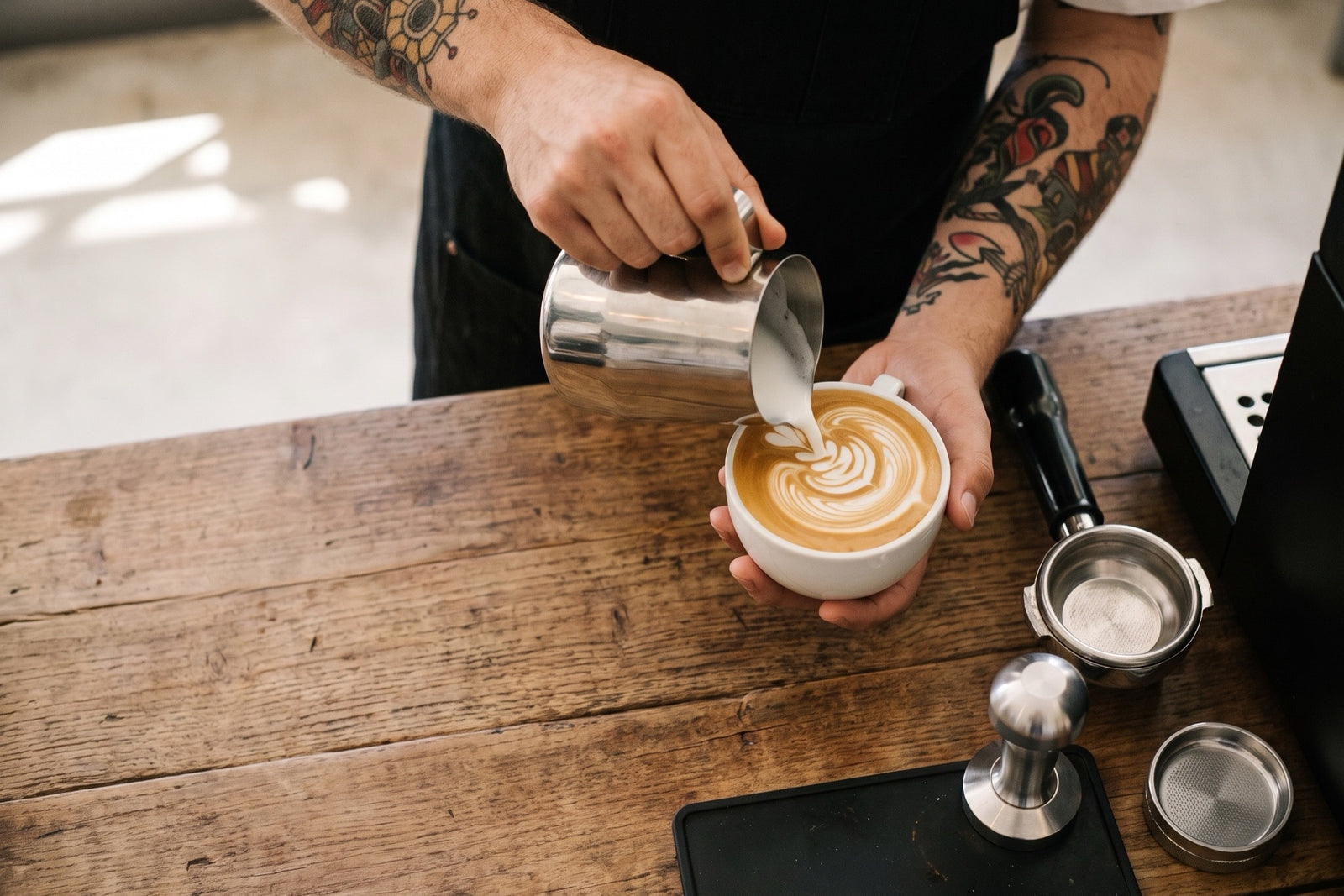 Barista vertiendo leche para latte art en una taza de Sufí Kafé